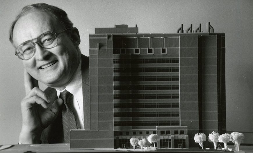 Dr. Bluemle smiling with a model version of the Bluemle Life Sciences Building
