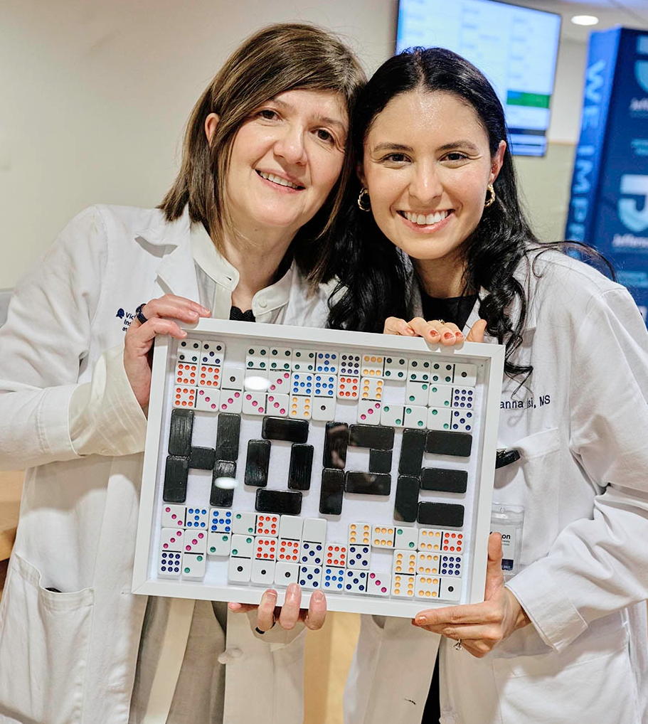 This image shows two people from the Weinberg ALS Center holding a frame with dominoes spelling out hope.