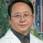 This image shows a portrait photo of Haifeng Yang, PhD in a white lab coat