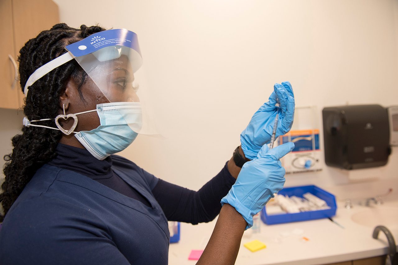 Employee preparing to administer a COVID-19 vaccine