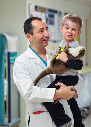 Dr. Jabbour in his white coat holding a child
