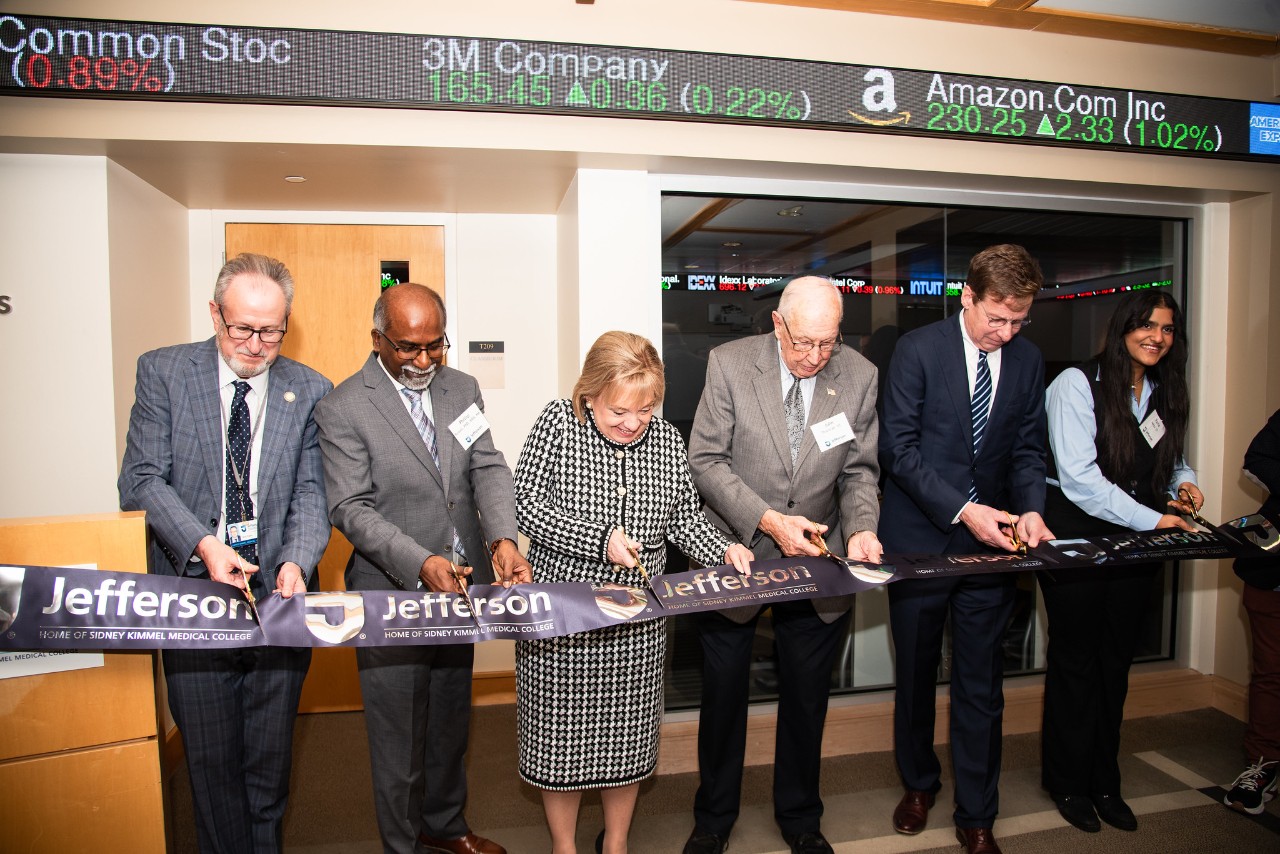 This image shows Dr. Susan Aldridge (center left), John Thackrah (center right), and others cutting the ribbon to open the new Thackrah Capital Markets Research Lab.
