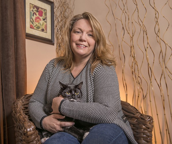 Melissa Bingham smiling at home, holding her cat