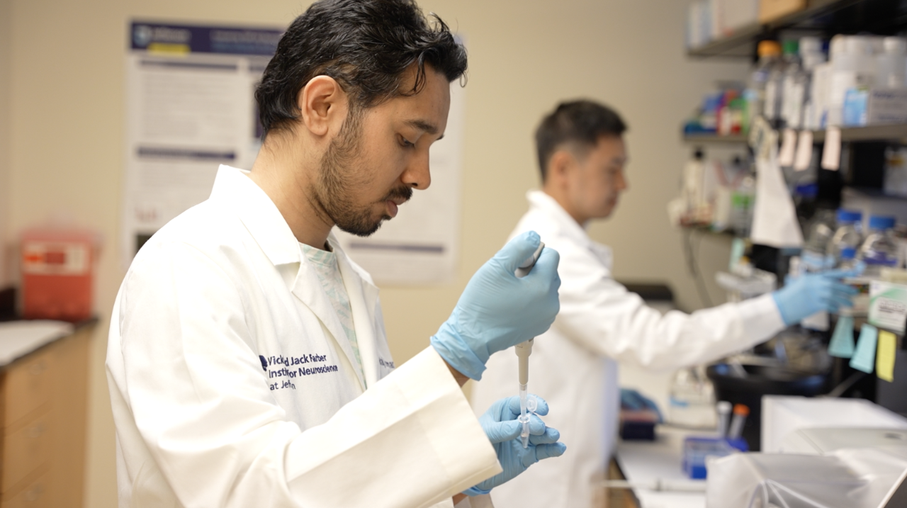 This image shows a researcher in a white lab coat dropped a liquid into a test tube at the Weinberg ALS Center.